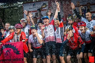 Grupa kolarzy w strojach sportowych świętuje sukces podczas zawodów Tatra Road Race.